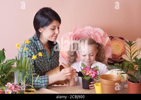 Cute child girl helps her mother to care for plants. Stock Photo