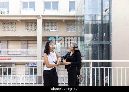 Two Indian women in an urban setting. Office colleagues standing together. Stock Photo