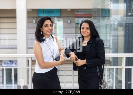 Two Indian women in an urban setting. Office colleagues standing together. Stock Photo