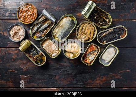 opened cans conserve with Saury, mackerel, sprats, sardines, pilchard, squid, tuna over wood table top view Stock Photo