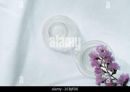 summer soft purple flower from the top of glass science flask and beaker for  natural cosmetic research fabric on white fabric background Stock Photo