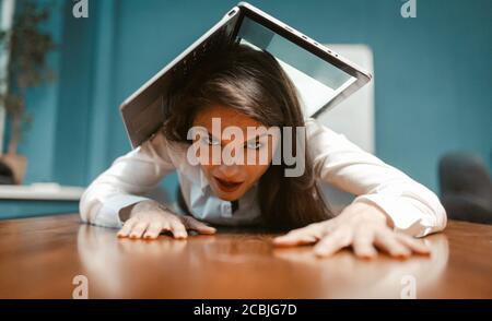 Crazy business woman covered with laptop while lying on office desk. Time to go on vacation. Fatigue resistance concept. Tinted image Stock Photo