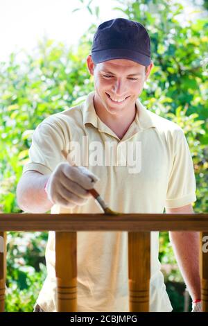 Young man painting wooden fence Stock Photo