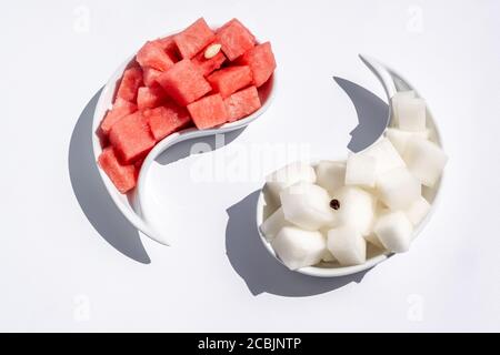 Ripe watermelon and melon, cut into cubes, are laid out on yin-yang plates. Juicy, ripe summer fruits. Bright light. Space for text. Stock Photo