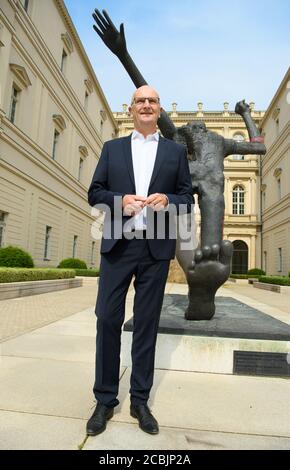 14 August 2020, Brandenburg, Potsdam: Dietmar Woidke (SPD), Minister President of Brandenburg, stands at the rear entrance to the Barberini Museum during his press tour next to the five-metre high bronze sculpture 'Der Jahrhundertschritt' (The Step of the Century) by Wolfgang Mattheuer. During the closing phase of the building, there was a view of the new exhibition 'Impressionism. The Hasso Plattner Collection', which will open on 07.09.2020. Potsdam is thus to become one of the most important centres of collections of Impressionist landscape painting worldwide outside of Paris. Photo: Soeren Stock Photo