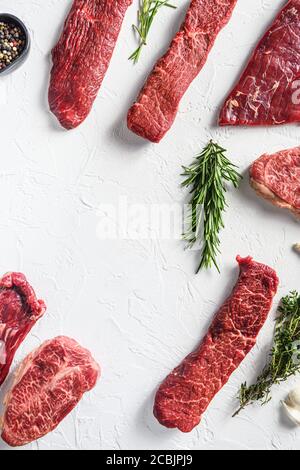 Set of different alternative types of raw beef steaks,on a white stone background top view concept frame in corners space for text in center vertical Stock Photo