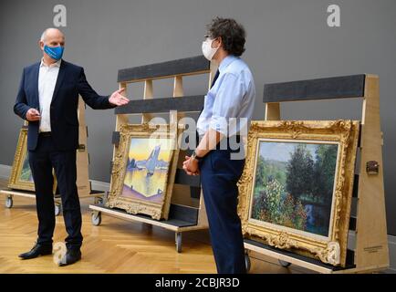 14 August 2020, Brandenburg, Potsdam: Dietmar Woidke (l, SPD), Minister President of Brandenburg, speaks alongside chief curator Michael Philipp during his press tour at the Barberini Museum. Behind them are the paintings 'The Port at Sundown, Opus 236 (Saint-Tropez 1892)' by Paul Signac and 'The Rose Trees in the Garden of Montgeron' (r, 1876) by Claude Monet. During the closing phase of the house there was a view of the new exhibition 'Impressionism. The Hasso Plattner Collection', which will open on 07.09.2020. Potsdam is thus to become one of the most important centres of collections of Im Stock Photo