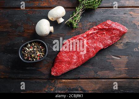 Whole tri tip steak with fresh seasoningsm thyme, organic tri-tip roast with fat marbled through the meat ready to roast or barbecue on rustic wooden Stock Photo