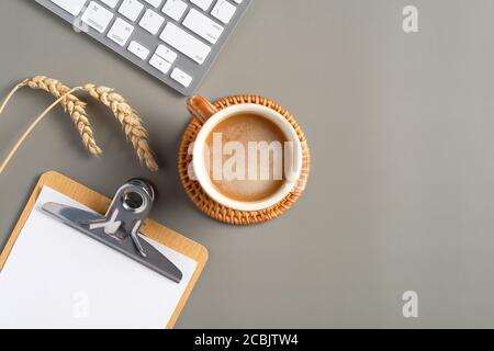 Office desk table top view. Flat lay coffee cup, computer keyboard, paper clipboard, wheat on green background. Modern freelancer workspace Stock Photo