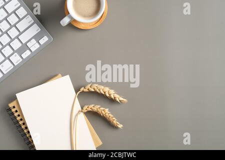 Modern workspace with pc keyboard, notebook, blank paper note, coffee cup, wheat on pastel green background. Office desk table, autumn style. Stock Photo