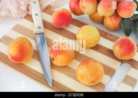 Organic apricots lying on a cutting board with a kitchen knife. Close up. Stock Photo