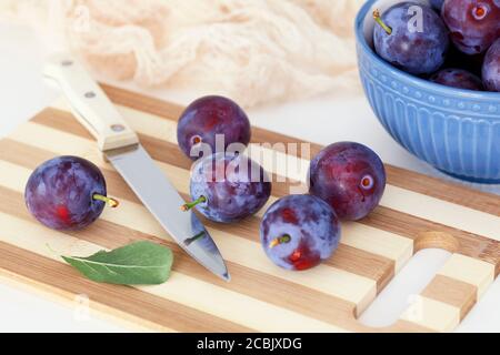 Plums lying on a cutting board with a kitchen knife. Close up. Stock Photo