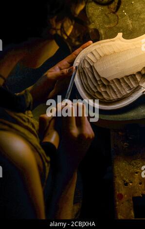 hands of artisan woman violin maker luthier working in the back table of a new hand made cremonese violin Stock Photo