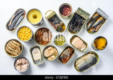 Assortment of canned preserves food in cans. On white rustic background conserve Saury, mackerel, sprats, sardines, pilchard, squid, tuna pinapple Stock Photo