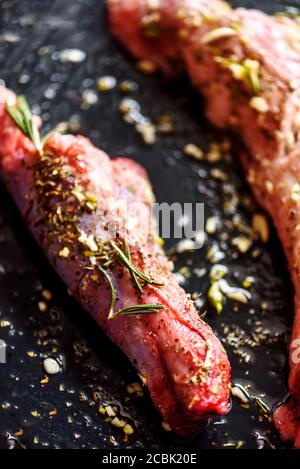 Lamb meat bbq preparation. Closeup of lamb chops with spices and rosemary on black rustic plate. Restaurant cuisine barbecue dish. Stock Photo