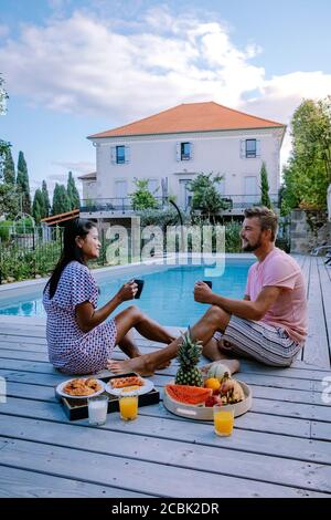 French vacation home with wooden deck and swimming pool in the Ardeche France. Couple relaxing by the pool with wooden deck during luxury vacation at