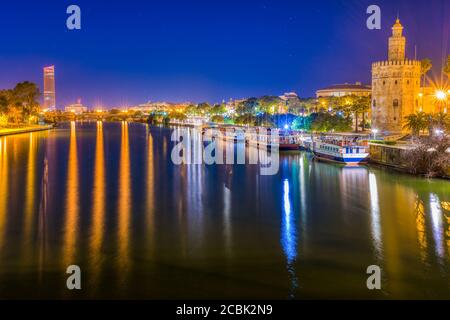 The Guadalquivir river and the Gold Tower (12th century) at night, Seville, Spain Stock Photo