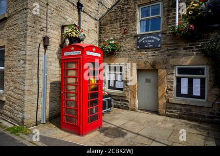 Hayfield village, High Peak, Derbyshire, Parish council building with defibrillator in a old red phonebox on Market Street Stock Photo