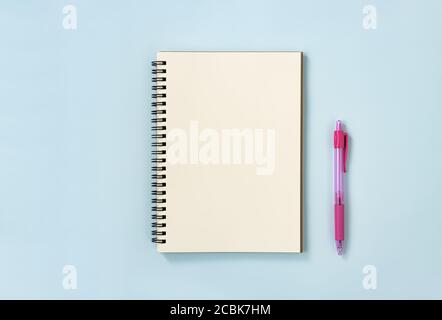 Spiral Notebook or Spring Notebook in Unlined Type and Pink Pen on Blue Pastel Minimalist Background. Spiral Notebook Mockup on Center Frame Stock Photo