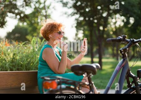 Mature woman using video call on her smartphone in the park Stock Photo