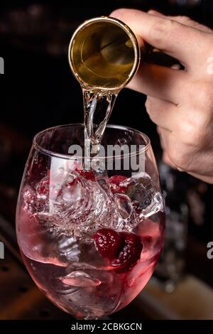 The bartender prepares a cocktail in the restaurant bar. The process of pouring alcohol into a glass Stock Photo