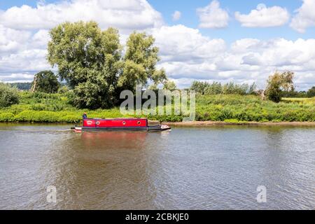 A barge or longboat cruising on the River Severn at Wainlode, Gloucestershire UK Stock Photo