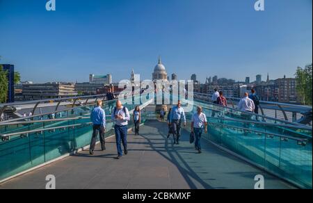 England, London, City workers crossing the Millennium Bridge with the dome of St Paul’s Cathedral in the background. Stock Photo