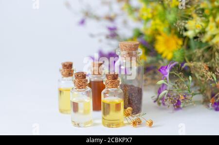 Essential oils in glass bottles with organic healing herbs and flowers in the background Stock Photo