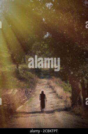 Person walking down country road in sunlight Stock Photo