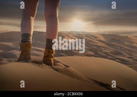 Womans feet on giant sand dune in the desert at sunset , low section, Abu Dhabi, UAE Stock Photo