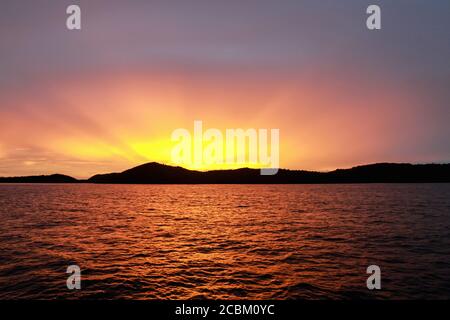 Sun setting over the equator in the Raja Ampat islands of West Papua in the Halmahera sea, Indonesia Stock Photo