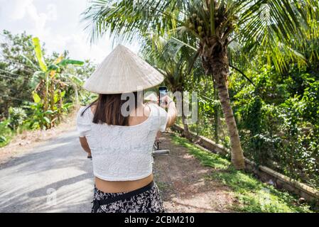 Woman wearing traditional rice hat, taking selfie, Tan Phong Island, Vietnam Stock Photo