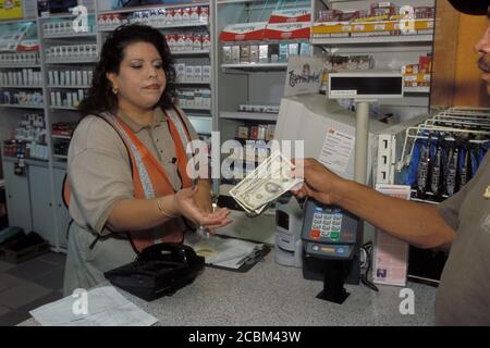 Austin, Texas USA, 2006: Female Hispanic clerk taking cash payment at an EXXON Mobil convenience store. ©Bob Daemmrich Stock Photo