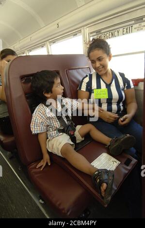 Mabank, Texas USA, August 21, 2006: Hispanic mother of Mabank Central Elementary School Head Start student shows her 4-year old child how to buckle a seat belt on the school bus. ©Bob Daemmrich Stock Photo