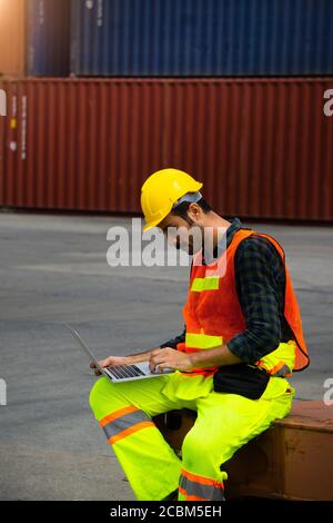 Industrial workers or engineers using computer laptop to control work in logistics business at container yard. Stock Photo