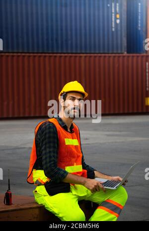 Industrial workers or engineers using computer laptop to control work in logistics business at container yard. Stock Photo