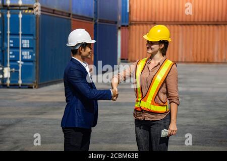 Business man and industrial worker woman shaking hands in background at container box Stock Photo