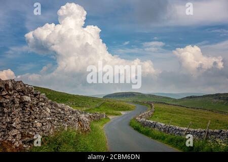 UK landscapes: Country lane in stunning scenery in the Yorkshire Dales National Park, heading over Malham Moor with thundercloud building