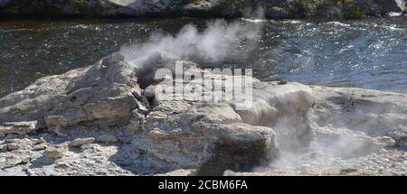 Late Spring in Yellowstone National Park: Mortal Geyser of the Morning Glory Group on the Bank of Firehole River in Upper Geyser Basin Stock Photo