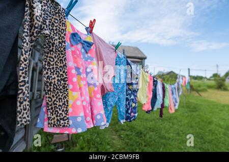 Clean, washed clothes are dried on a rope with clothespins in the outdoors in the village. Lifestyle. Stock Photo