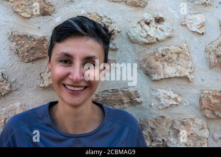 portrait of mature woman smiling with stone wall in the background Stock Photo