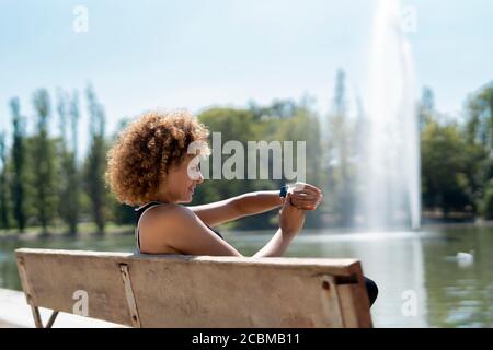 woman on a bench by the lake using her smartwatch Stock Photo
