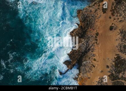 top view of sea waves hitting rocks on the beach with turquoise blue ...