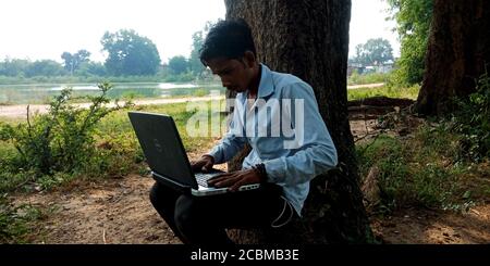 DISTRICT KATNI, INDIA - OCTOBER 23, 2019: An indian village boy operating laptop at natural background, concept for digital learning technology awaren Stock Photo