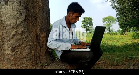 DISTRICT KATNI, INDIA - OCTOBER 23, 2019: An indian village boy operating laptop at natural background, concept for digital learning technology awaren Stock Photo