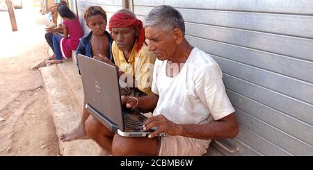 DISTRICT KATNI, INDIA - OCTOBER 23, 2019: Group of indian village peoples working on laptop at open area background, concept for digital learning tech Stock Photo