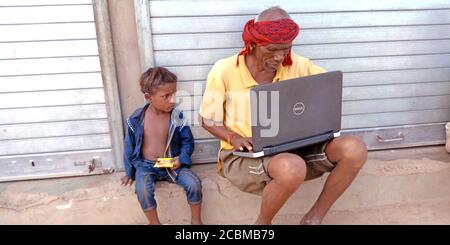 DISTRICT KATNI, INDIA - OCTOBER 23, 2019: An indian village old man teaching laptop to his grand son at open area background, concept for digital lear Stock Photo