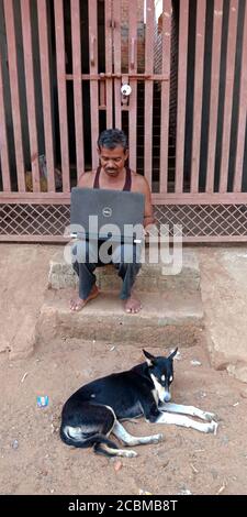 DISTRICT KATNI, INDIA - OCTOBER 23, 2019: An indian village labour operating laptop at open area background, concept for digital learning technology a Stock Photo