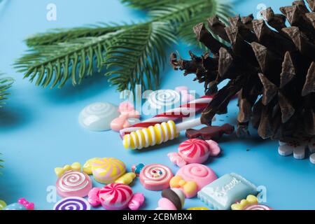 Pine cone, needles, branch of a Christmas tree and candy toys on blue background Stock Photo