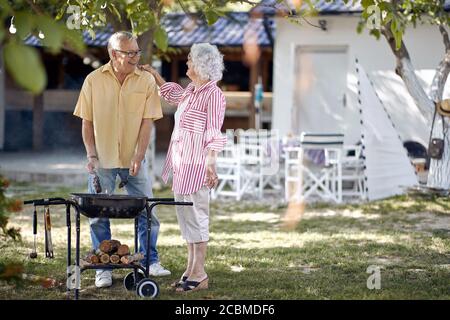 Happy Senior Couple Outside Cooking on A Summer Barbecue. Stock Photo